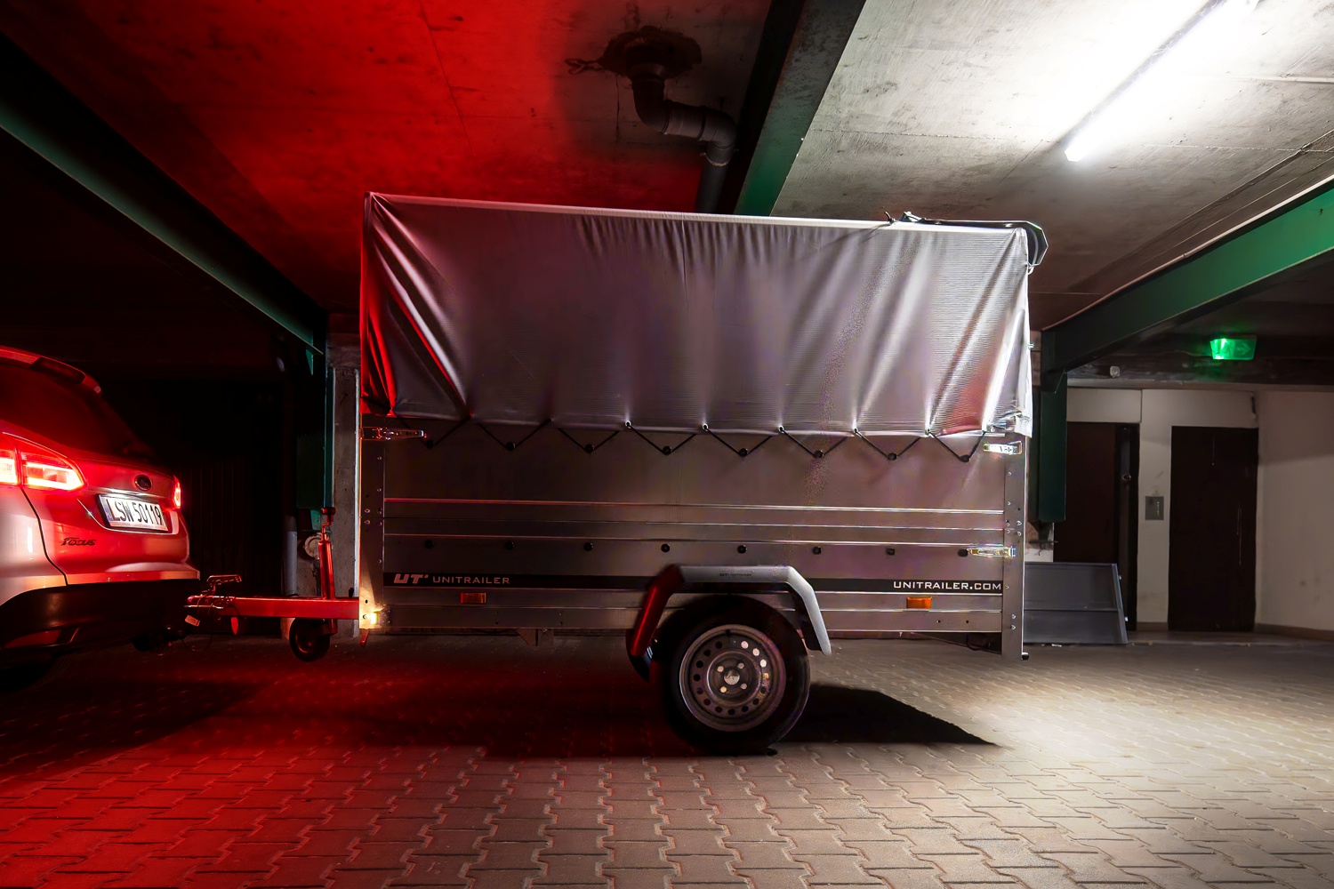 Ein Anhänger in einer dunklen Garage. Rote Parkleuchten an.